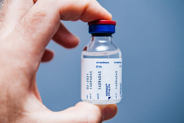 PARIS, FRANCE - OCT 2, 2018: Doctor holding Visipaque - Iodixanol package containing the contrast agent for the medical intervention under CT scanner on doctors table - iodine-containing non-ionic