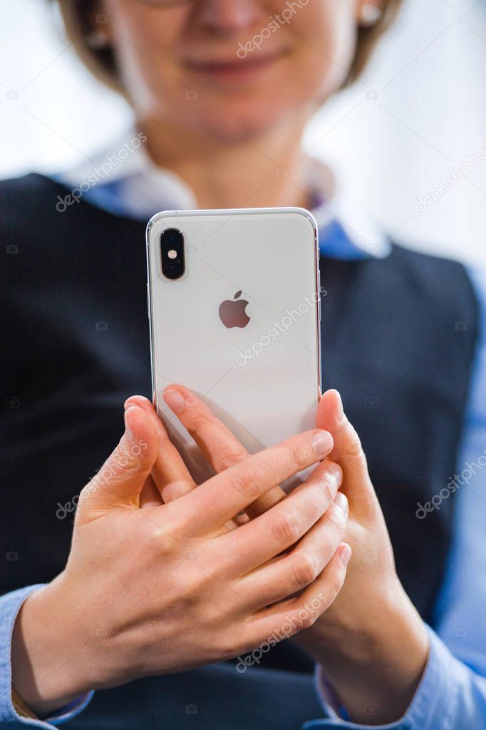 PARIS, FRANCE - OCT 2, 2018: Happy business woman working on the new Apple iPhone Xs Max smartphone telephone from Apple Computers with all home apps on OLED display - Apple Computers Logo