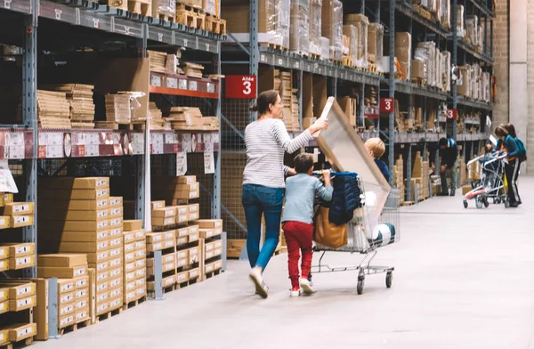 Mãe solteira fazendo compras na loja de móveis IKEA empurrando carrinho — Fotografia de Stock