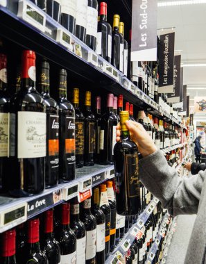 Strasbourg, Fransa - 30 Aralık 2017: zarif Fransız kadın kırmızı şarap alkollü içki şarap, şampanya ve viski şarap bölümü büyük bir Fransız süpermarket satın alma