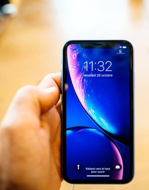 Paris, Fransa - 26 Ekim 2018: en son mavi iphone Xr smartphone denize indirmek gün pov, yeni smartphone ile sıvı Retina dikey sırasında Apple Store Computers'ta tutan adam el