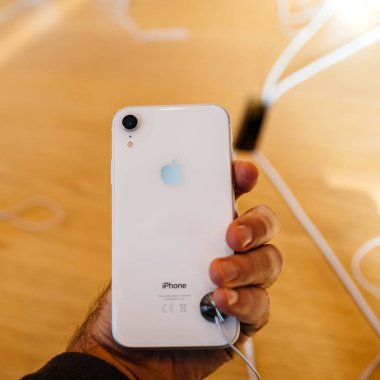 Paris, Fransa - 26 Ekim 2018: Yeni iphone Xr akıllı telefon Apple Store bilgisayarlarda bulunan glash arka gümüş logosu ile erkek el denize indirmek gün boyunca