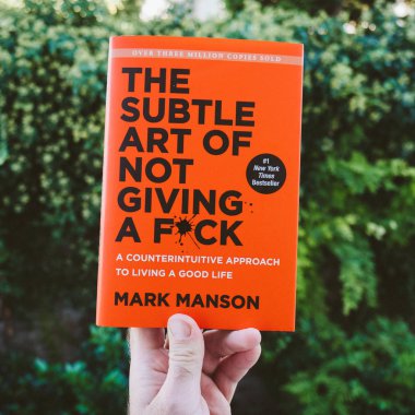 Paris, Fransa - 4 Ekim 2018: Kadın unboxing yeni kitap yeşil bir arka plana dayanır Mark Manson tarafından bir bok vermek değil ince sanat