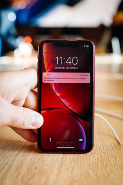 Paris, Fransa - 26 Ekim 2018: Erkek el ahşap masa en son kırmızı iphone Xr akıllı telefon Apple Store bilgisayarlar üzerinde dikey görüntü sırasında denize indirmek gün - müşterileri, arka planda tutarak