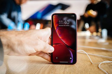 Paris, Fransa - 26 Ekim 2018: Erkek el ahşap masa en son kırmızı iphone Xr akıllı telefon Apple Store bilgisayarlar üzerinde denize indirmek gün boyunca - müşteriler arka planda tutarak 