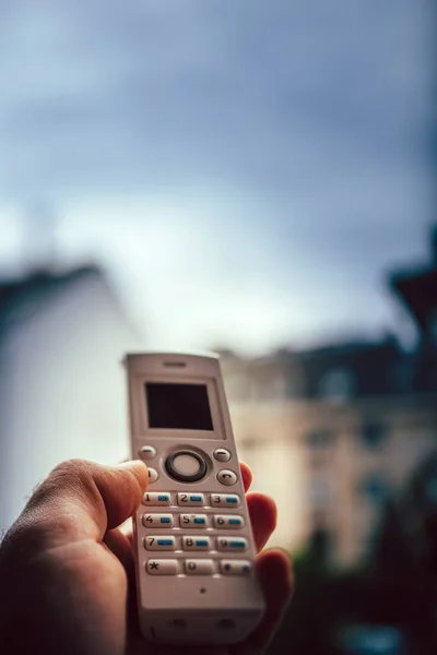 Man hand met draadloze telefoon bellen kantoor aan huis — Stockfoto