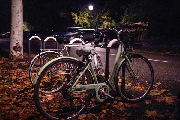Dwa zabytkowe rowery zaparkowane na ulicy w nocy — Zdjęcie stockowe