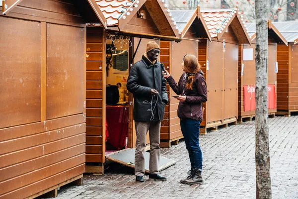 Mujer entrevistando a hombre de etnia negra en Navidad MArket — Foto de Stock