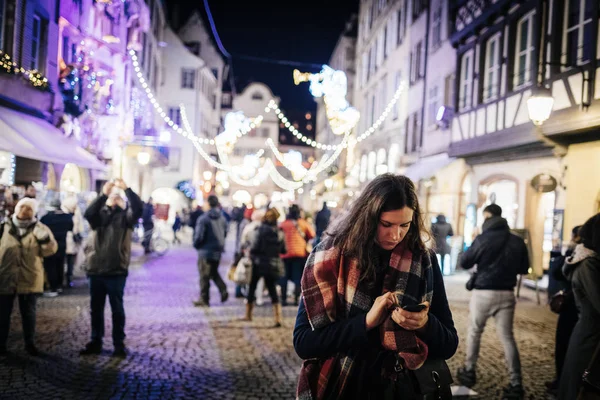 Žena používající smartphone v Štrasburku vánoční trh za soumraku — Stock fotografie