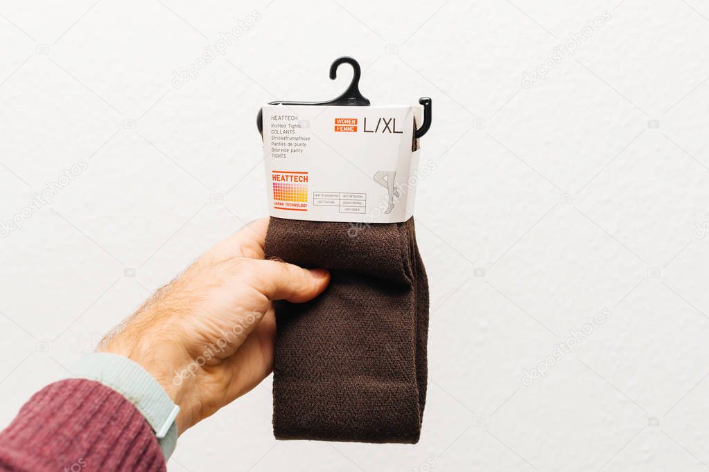 Paris, France - Dec 21, 2018: Man holding against white background a new package with Heattech knitted tights manufactured by Uniqlo Japanese casual wear designer, manufacturer and retailer
