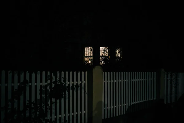 Night street scene with light in windows fence