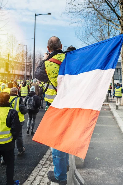 Hombre con bandera nacional francesa mirando cientos de chalecos amarillos Gilets Jaunes —  Fotos de Stock