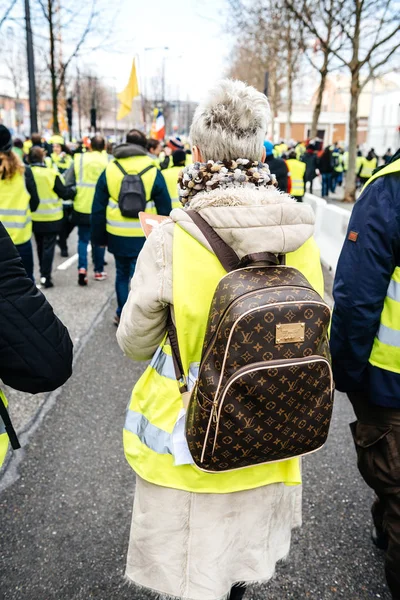 Kobieta z luksusowych plecak Louis Vuitton w żółtej kamizelki protestu — Zdjęcie stockowe