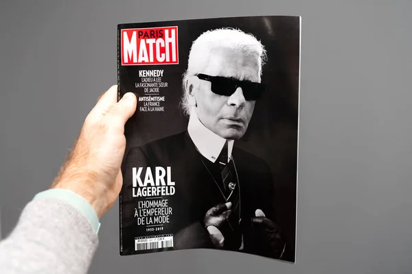 Hombre sosteniendo Paris Match revista francesa con Karl Lagerfeld retrato — Foto de Stock