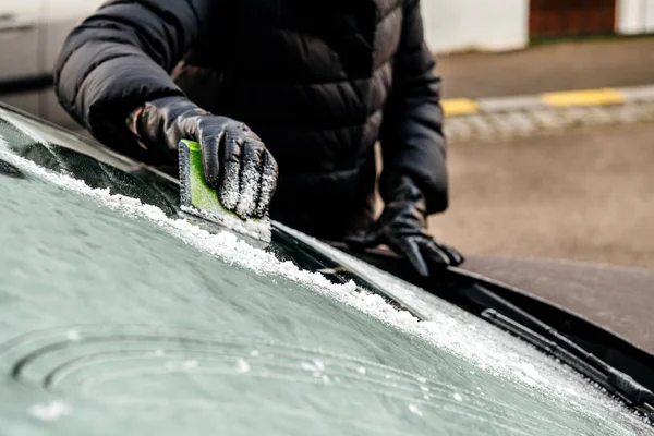Woman cleaning car windshield from frost