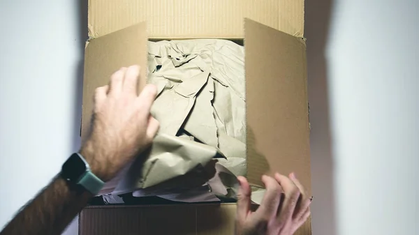 Мужчина распаковывает коробку, доставленную посылкой — стоковое фото