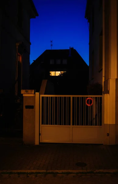 Illuminated window at dusk with house roof — Stock Photo, Image