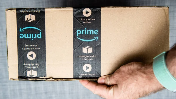 Ruka držící lepenkovou krabici s amazonským logotypem — Stock fotografie