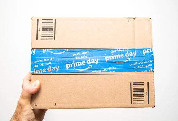 Hand van de man die tegen witte Amazon Prime dag kartonnen doos — Stockfoto