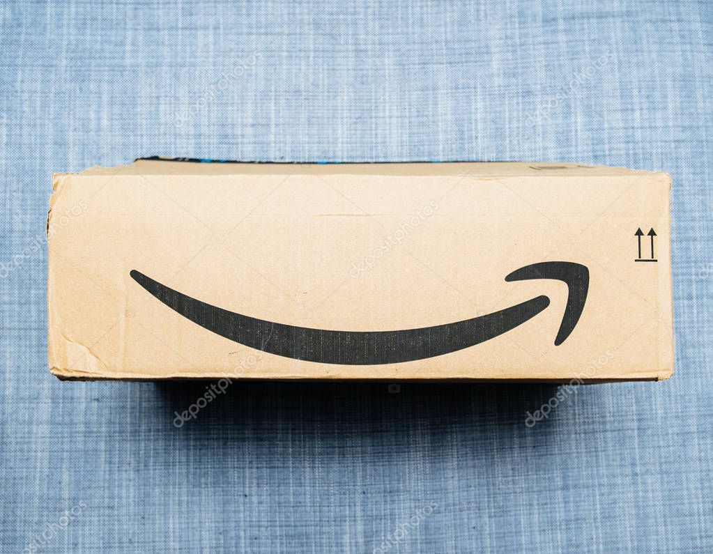 Paris, France - Jun 11, 2018: Freshly delivered Amazon Prime cardboard box featuring big smile logotype on the textile couch background