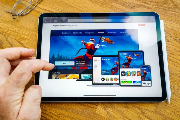 Ο άνθρωπος χρησιμοποιώντας ανάγνωση σχετικά με Arcade συνδρομής στην ιστοσελίδα της Apple το ipad Pro tablet — Φωτογραφία Αρχείου