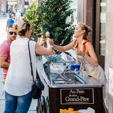 Genç Sarışın kadın müşteri için dondurma koni hazırlanıyor