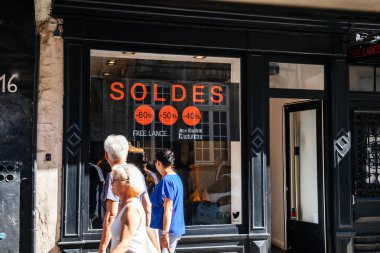 Pencere önünde soldes satış önünde yürüyen insanlar