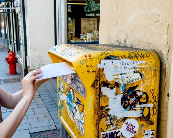 Mujer inserta una carta dentro del buzón francés amarillo la poste —  Fotos de Stock