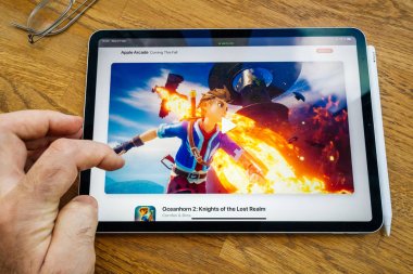 İpad profesyonel tablet Apple Web sitesinde Arcade aboneliği hakkında okuma kullanan adam