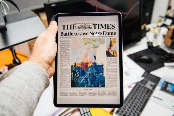 Мужчина читал на iPad Pro о пожаре в соборе Парижской Богоматери — стоковое фото