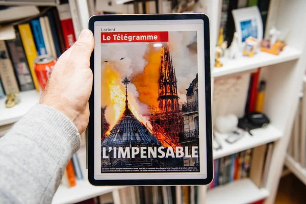 Mann liest auf ipad pro über notre-dame de paris fire — Stockfoto