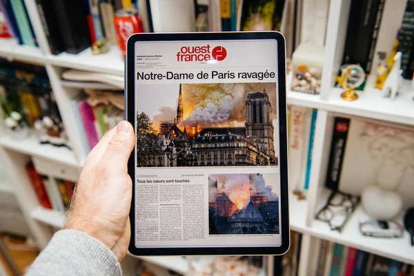ノートルダム・ド・パリ火災ウエストフランスについてiPad Proで読んでいる男 — ストック写真