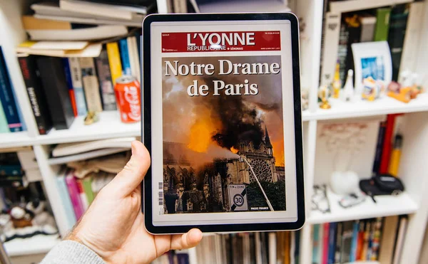 Mann liest auf ipad pro über notre-dame de paris fire — Stockfoto