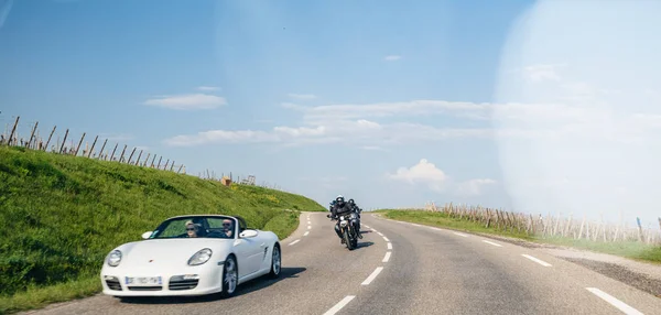 Group of motorcyclists following couple driving in white porsche — Stock Photo, Image