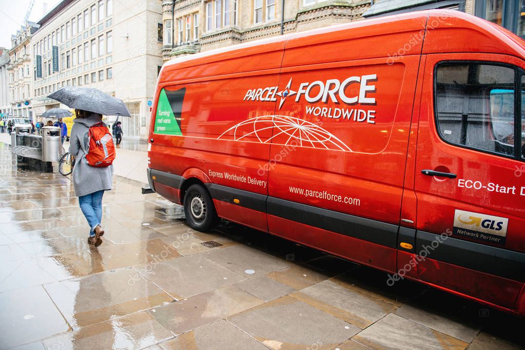 Oxford, United Kingdom - Mar 3, 3017: Rainy day with pedestrians in front of GLS Partner Parcel Force Delivery Parcel red van in front of Leon restaurant and Express Worldwide Delivery sign