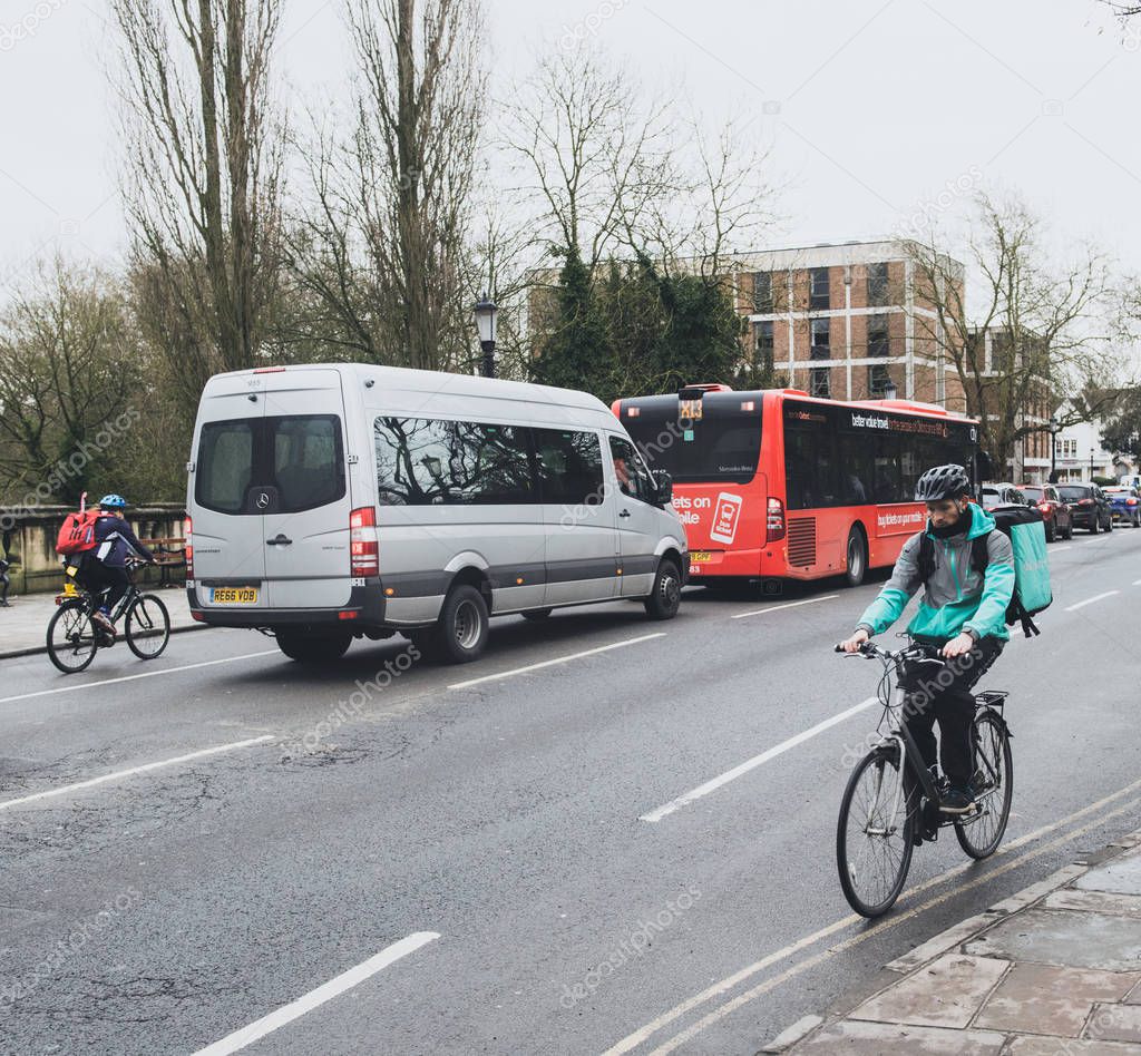 Oxford, United Kingdom - Mar 3, 3017: Fast young male cyclist delivering food fast to client via Deliveroo App - commuting fast in the university city with big thermo bag with Deliveroo logo