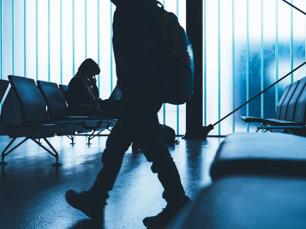 Man walking in front of business woman working in empty airport terminal — Stock Photo, Image