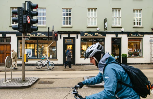 Женщина в шлеме на велосипеде быстро передвигается по Британской улице — стоковое фото