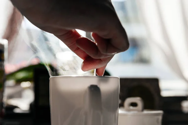 Mujer sosteniendo cucharadita dentro de taza de café blanco —  Fotos de Stock