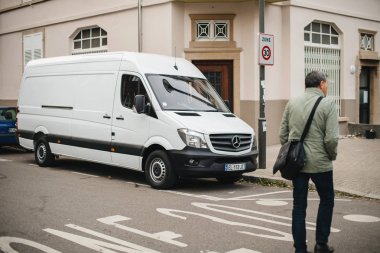 Yetişkin adam beyaz Mercedes-Benz Sprinter van önünde caddeden karşı karşıya 