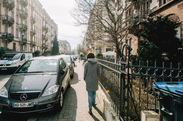 Rückansicht einer jungen Frau im Wollmantel, die auf der französischen Straße spaziert — Stockfoto