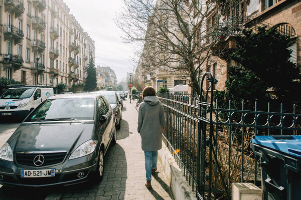 Rear view of young woman in wool coat walking on French stree