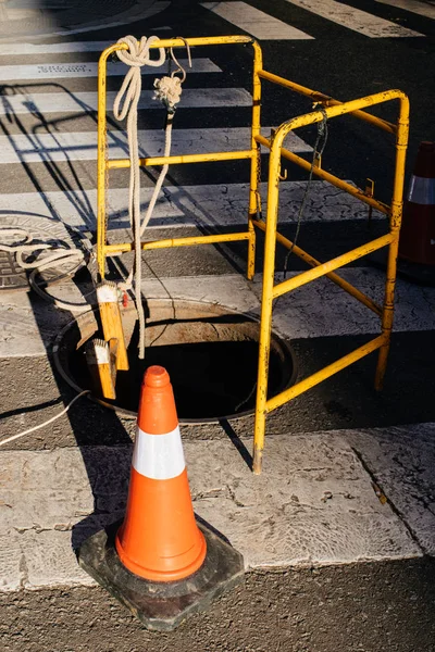 Cono de construcción naranja de advertencia de calle cerca de alcantarilla —  Fotos de Stock