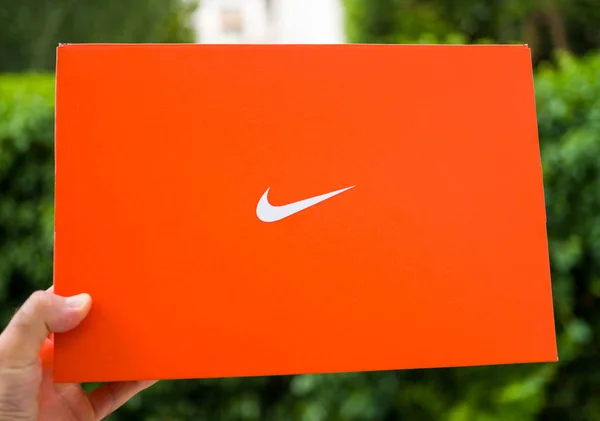 Uomo mano tenendo nuova scatola di cartone Nike contro parco verde — Foto Stock