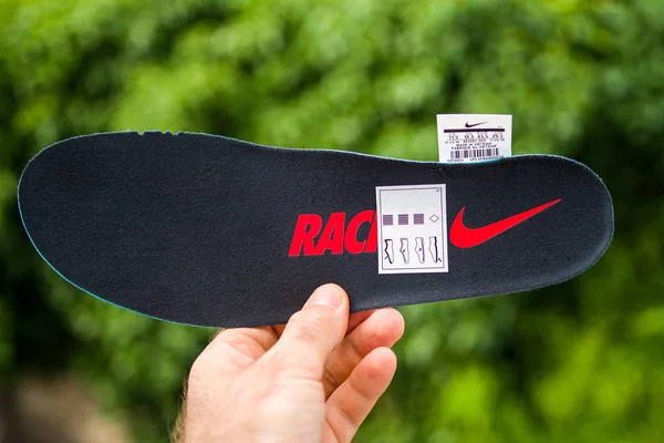 Mužová ruka držící Nike běh boty jediný závodní logotyp — Stock fotografie