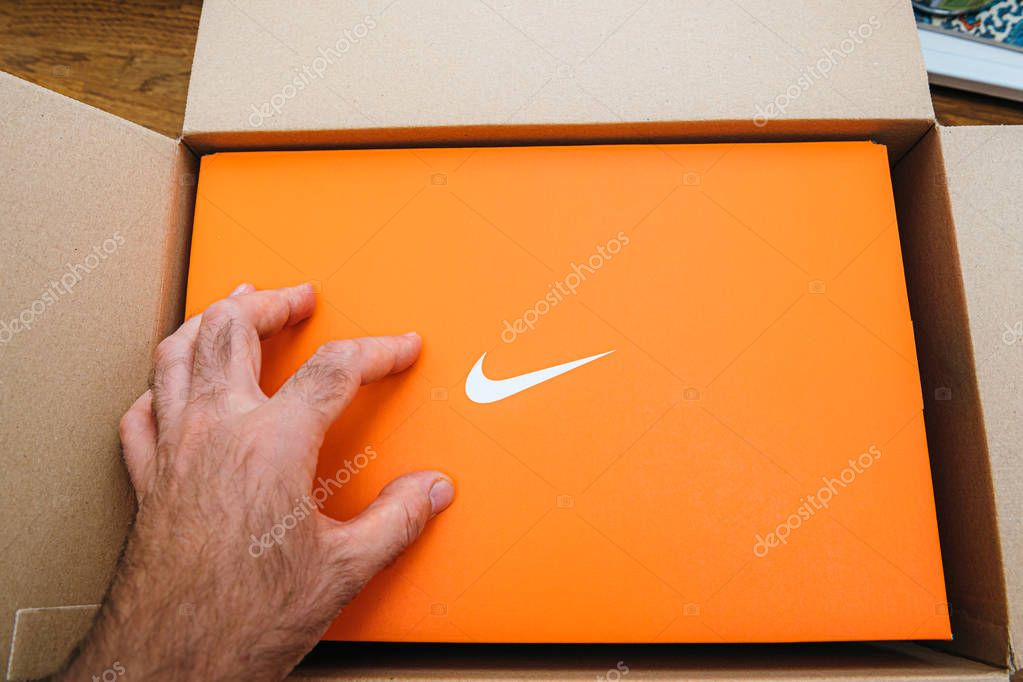 Paris France - Jul 13 2019: Man hand Above view unboxing unpacking sport running shoes equipment manufactured byu Nike sportswear - cardboard box open with white logotype