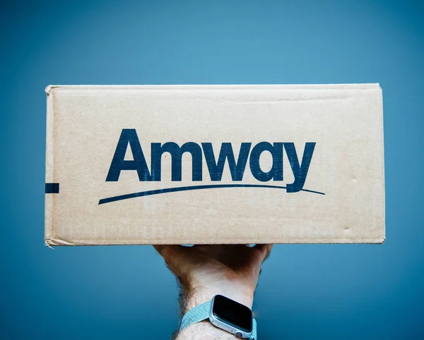 Paris, Frankreich - 2. Juli 2019: Mann hält Hand vor grauen Hintergrund Pappschachtel mit amway Schriftzug blauer Hintergrund — Stockbild Paketkasten mit amway Schriftzug blauer Hintergrund — Stockfoto