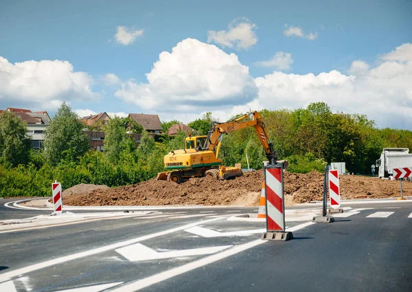 Рабочие экскаватора Либхерра строят новую кольцевую дорогу во французской деревне — стоковое фото