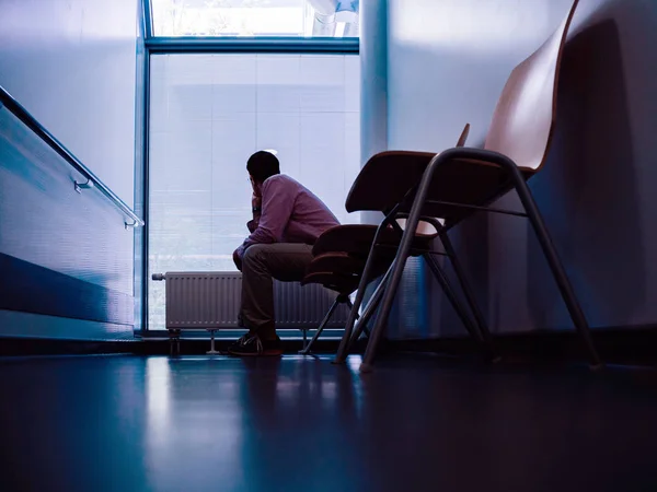 Одинокий пациент, сидящий в холле современной больницы — стоковое фото