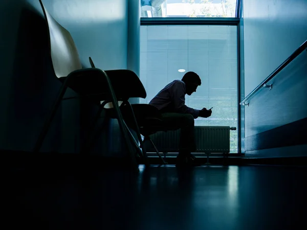 Homem usando smartphone na sala de espera do hospital — Fotografia de Stock